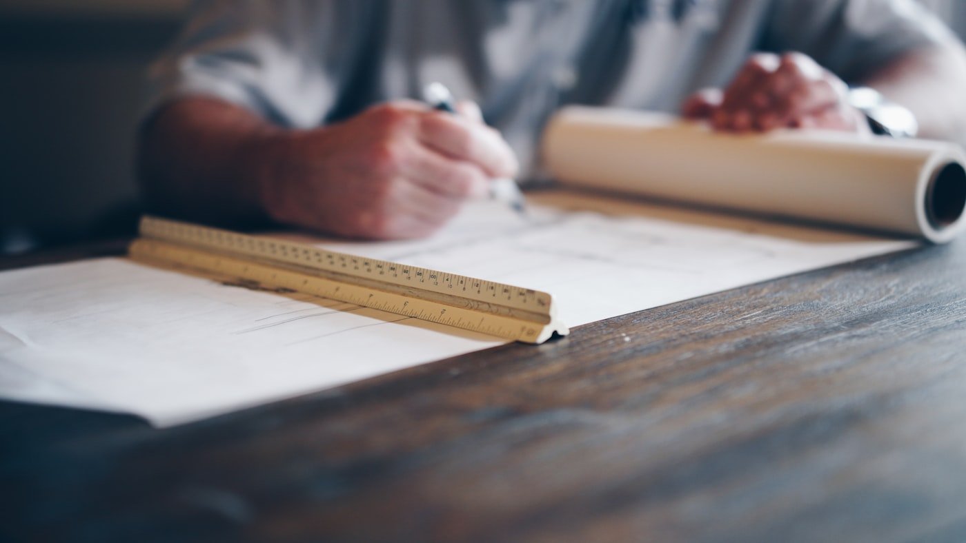 Hands drafting over architectural plans